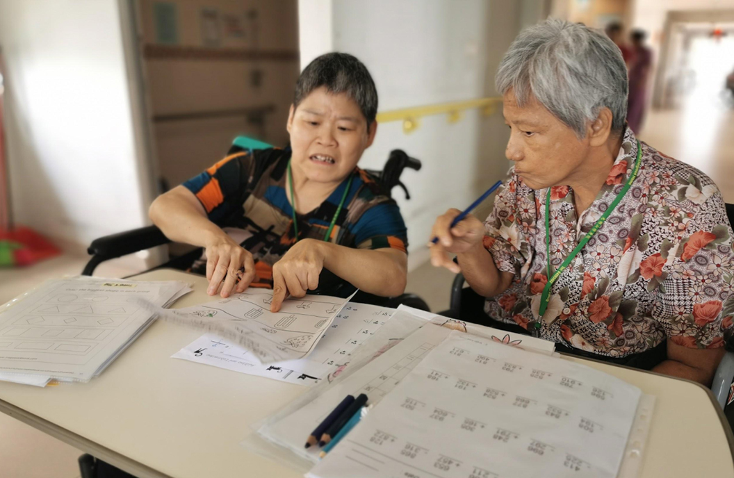 Resident See Ee showing Rose her homework from the week before.