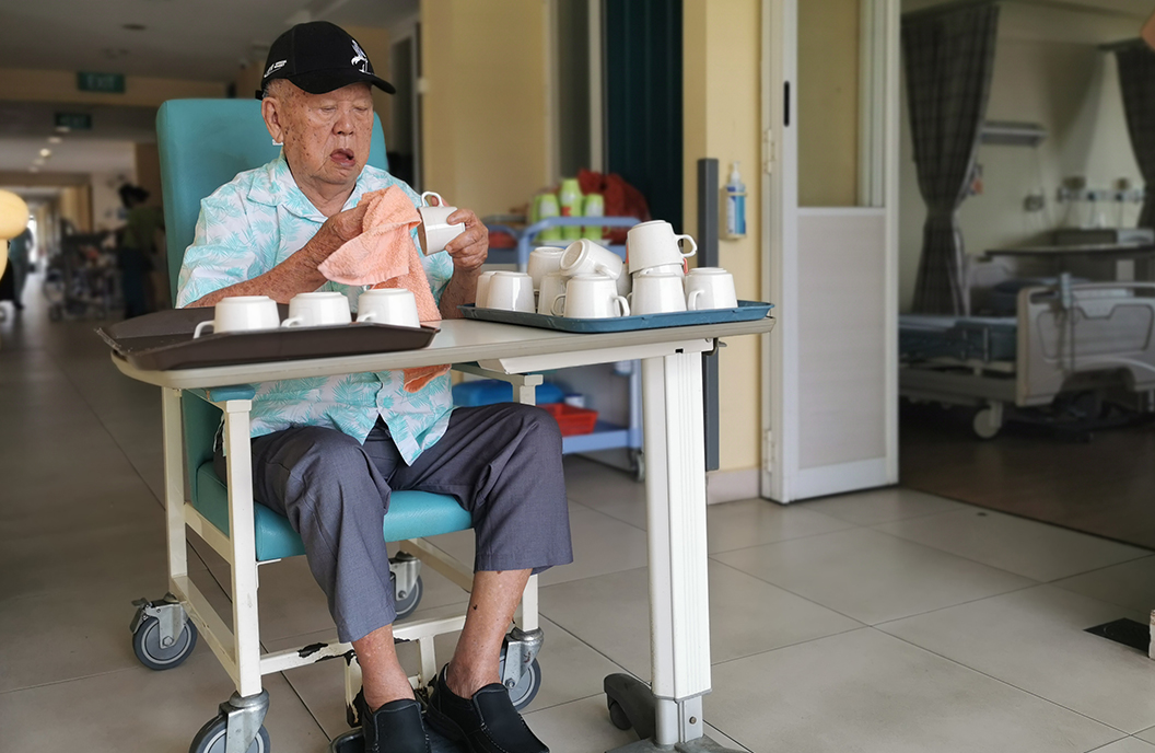 Bright Hill resident Goh Ah Huan helps with cleaning and drying cups.